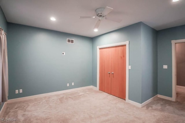 unfurnished bedroom featuring light carpet, a closet, and ceiling fan