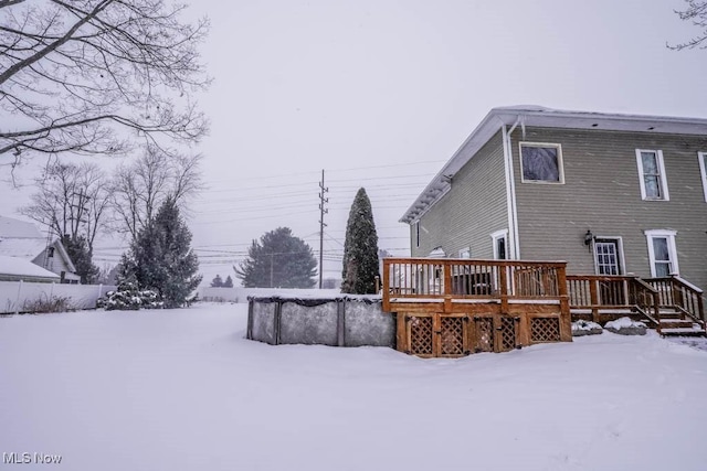 snow covered back of property featuring a deck