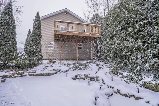 snow covered back of property featuring a wooden deck