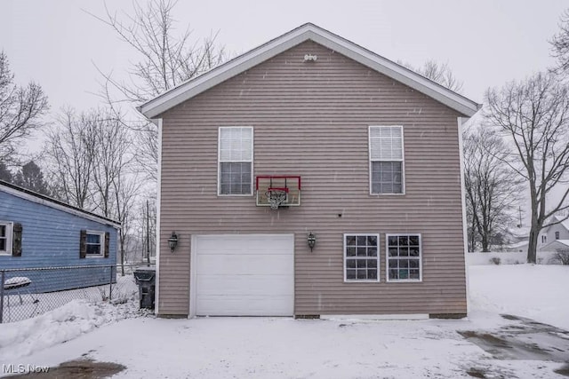 snow covered rear of property featuring a garage