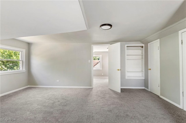 spare room with built in shelves and carpet floors