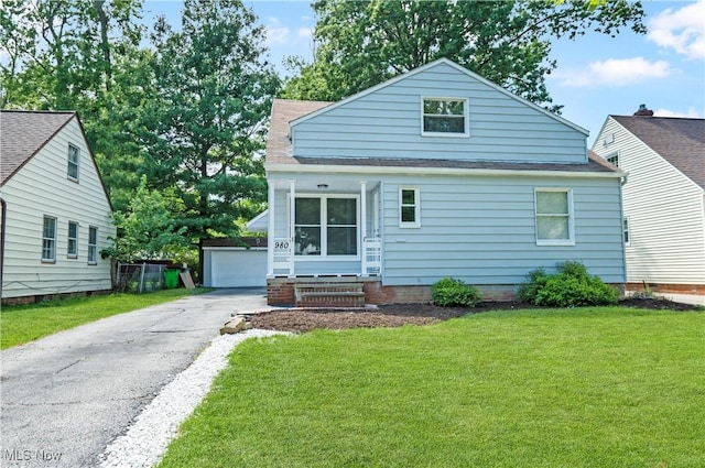 bungalow-style home with a front lawn, a garage, and an outbuilding