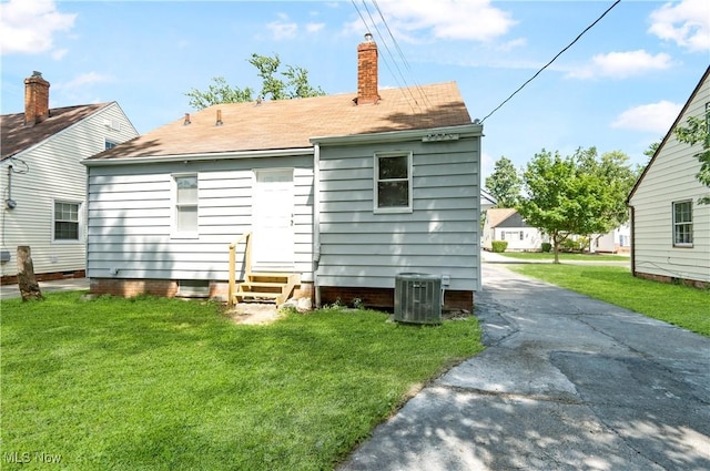 back of property featuring a lawn and central AC