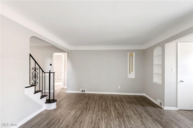 spare room with dark wood-type flooring and built in features