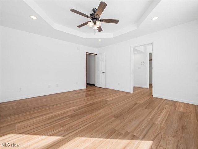 interior space featuring light wood-type flooring, ceiling fan, and a tray ceiling