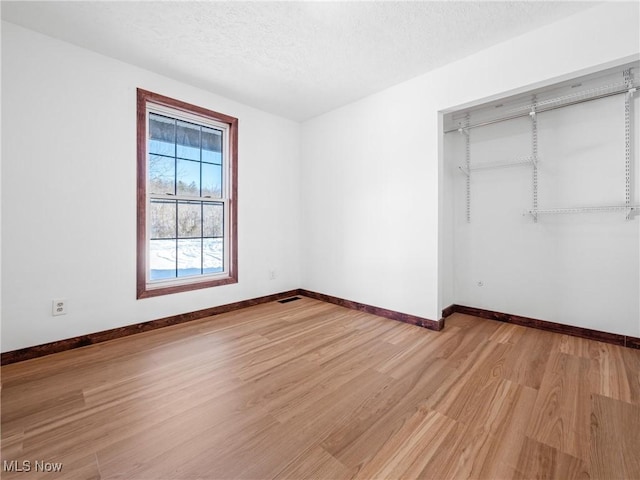 unfurnished bedroom featuring a closet, a textured ceiling, and light wood-type flooring