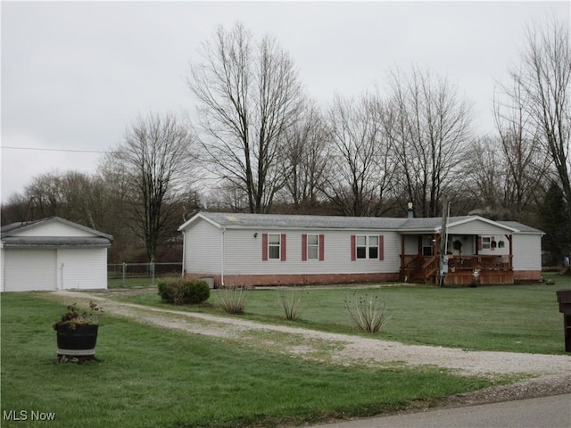 manufactured / mobile home featuring an outbuilding, a detached garage, a front lawn, and dirt driveway