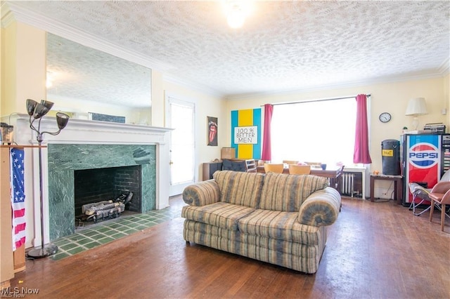 living room with a textured ceiling, dark hardwood / wood-style flooring, ornamental molding, and a fireplace