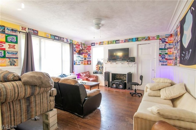 living room featuring a textured ceiling, ceiling fan, crown molding, and dark wood-type flooring