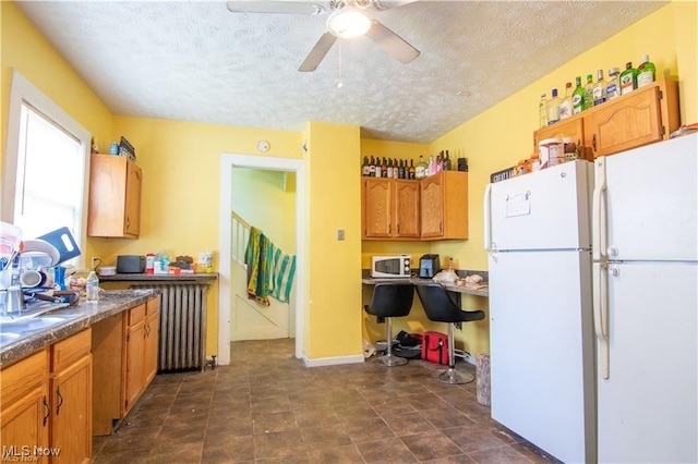 kitchen with white refrigerator, a textured ceiling, ceiling fan, and radiator heating unit