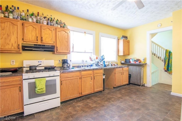 kitchen featuring a textured ceiling, ceiling fan, gas range gas stove, and radiator heating unit