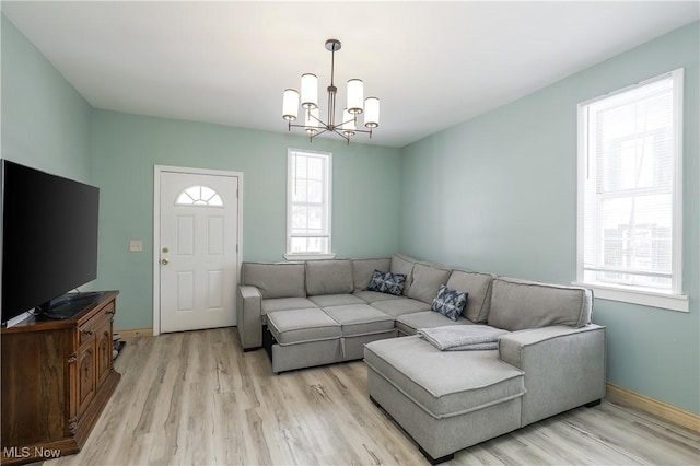 living room with a notable chandelier, light hardwood / wood-style floors, and a healthy amount of sunlight