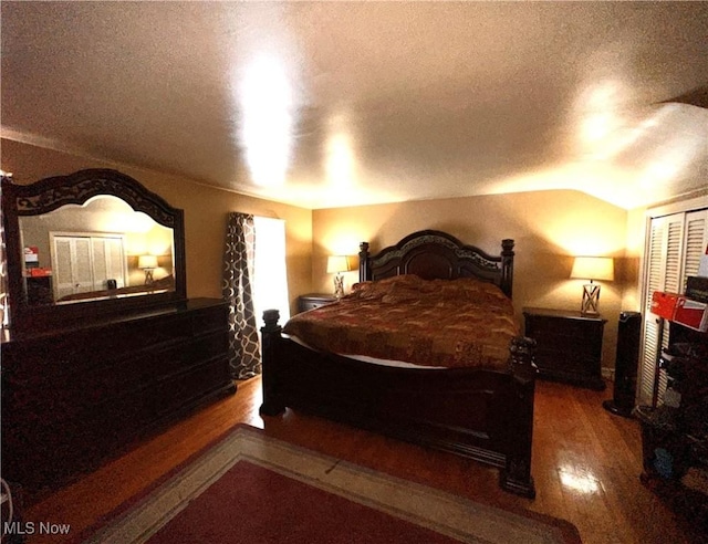 bedroom featuring a textured ceiling, wood-type flooring, vaulted ceiling, and a closet