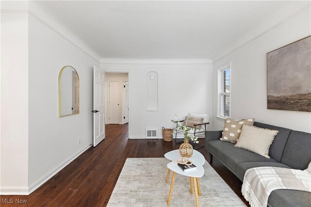 living room with ornamental molding and dark wood-type flooring