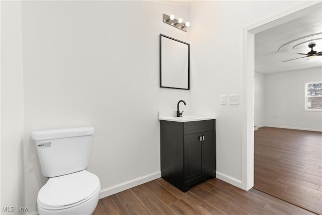 bathroom featuring toilet, vanity, hardwood / wood-style floors, and ceiling fan