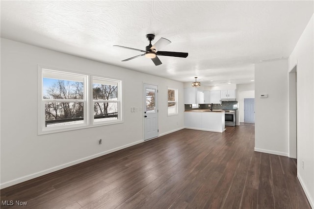 unfurnished living room with dark wood-type flooring, ceiling fan, and sink