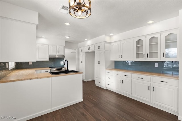 kitchen featuring kitchen peninsula, dark hardwood / wood-style floors, sink, white cabinetry, and backsplash