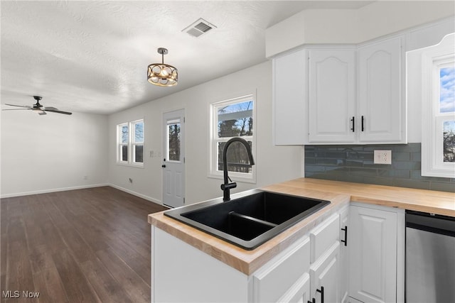 kitchen with sink, white cabinets, wood counters, backsplash, and hanging light fixtures