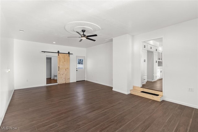 unfurnished room featuring dark wood-type flooring, ceiling fan, and a barn door