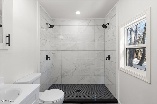 bathroom with toilet, vanity, and tiled shower