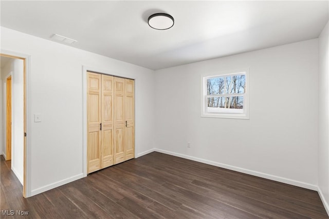 unfurnished bedroom with a closet and dark hardwood / wood-style floors