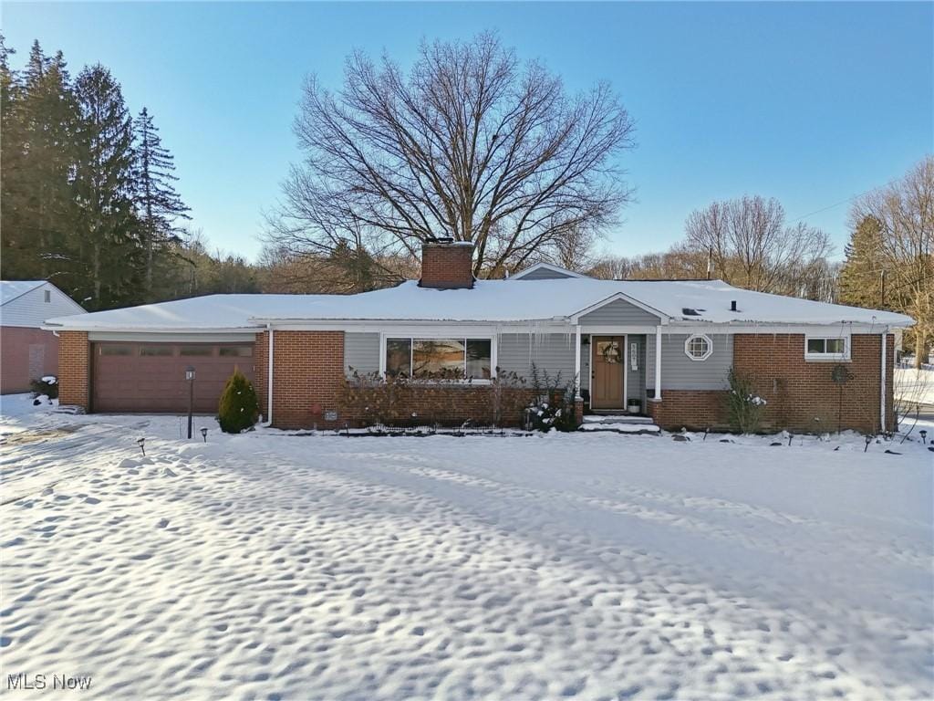 ranch-style home with brick siding, a chimney, and an attached garage