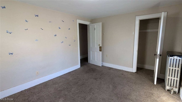 unfurnished bedroom featuring radiator heating unit, carpet flooring, and a closet