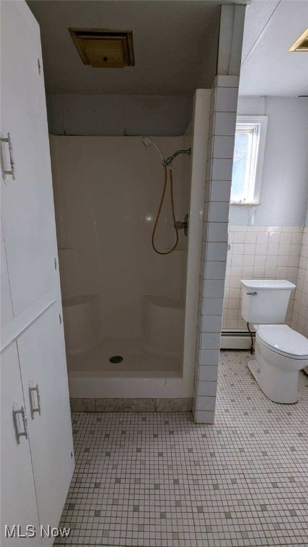 bathroom with toilet, walk in shower, tile walls, a baseboard heating unit, and tile patterned floors