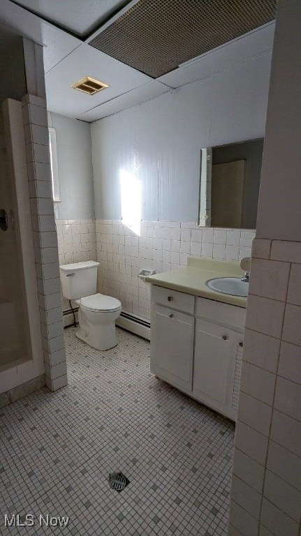 bathroom with toilet, tile patterned flooring, tile walls, and a baseboard radiator