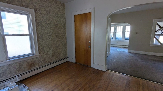 unfurnished room with baseboard heating and dark wood-type flooring