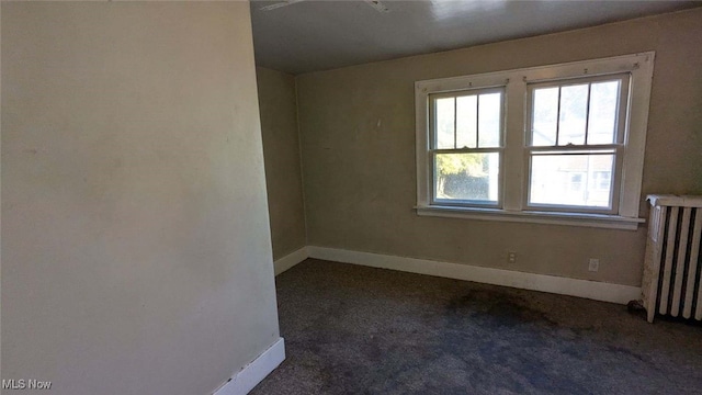 carpeted empty room featuring radiator heating unit