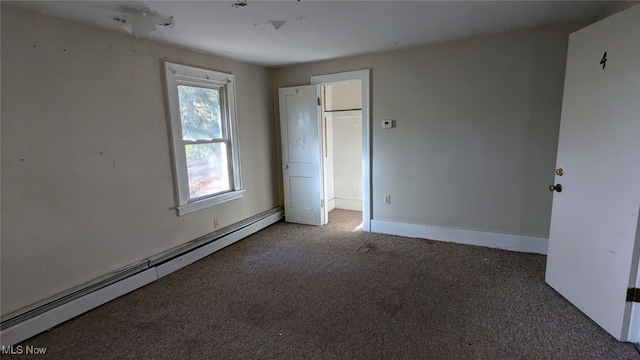 unfurnished bedroom with a baseboard heating unit and dark carpet