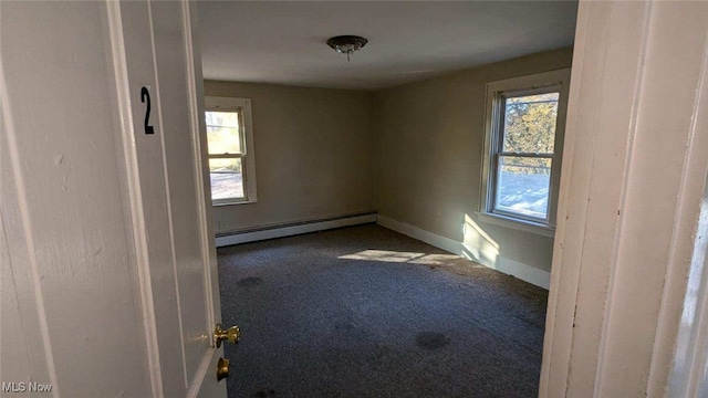 carpeted empty room featuring a baseboard heating unit