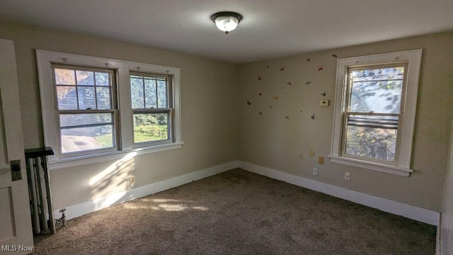 empty room featuring plenty of natural light and dark colored carpet