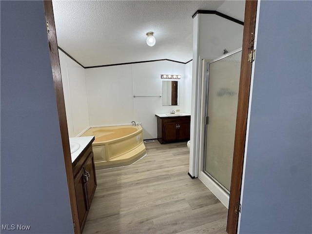 bathroom with a textured ceiling, separate shower and tub, vanity, and hardwood / wood-style flooring