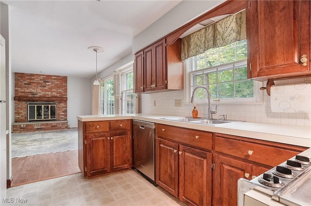 kitchen featuring sink, a fireplace, dishwasher, kitchen peninsula, and hanging light fixtures