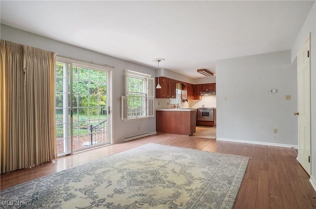 kitchen featuring sink, decorative light fixtures, hardwood / wood-style floors, stainless steel range, and baseboard heating