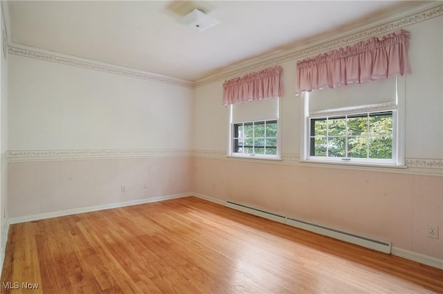 spare room with hardwood / wood-style floors and a baseboard heating unit