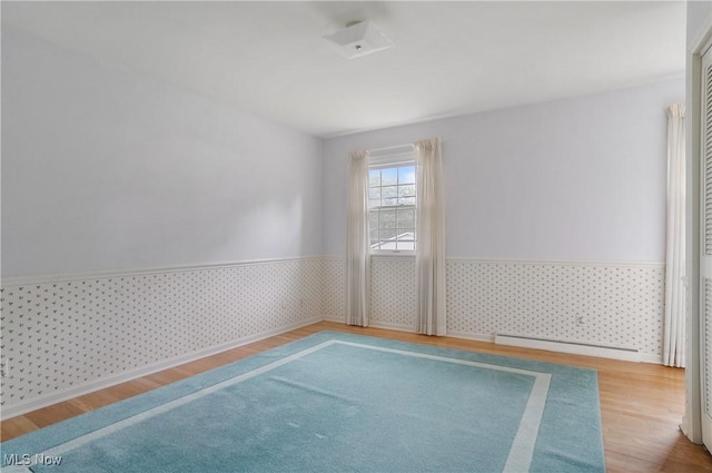 spare room with a baseboard radiator and light hardwood / wood-style flooring