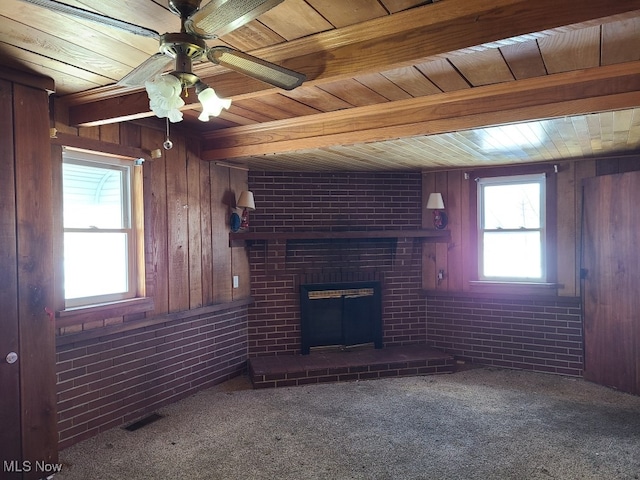 unfurnished living room featuring brick wall, wood walls, ceiling fan, and plenty of natural light