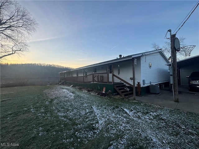 back house at dusk featuring central air condition unit and a lawn