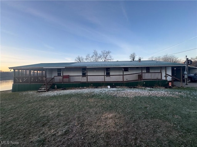 back house at dusk featuring a lawn