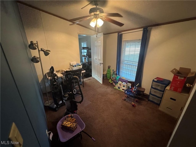 interior space with a textured ceiling, dark colored carpet, ceiling fan, and crown molding