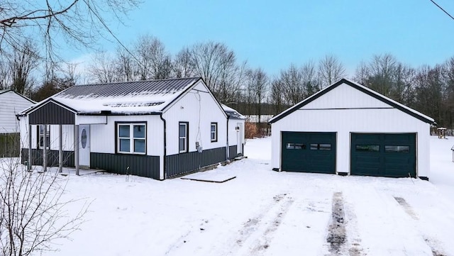 snow covered property featuring an outdoor structure and a garage