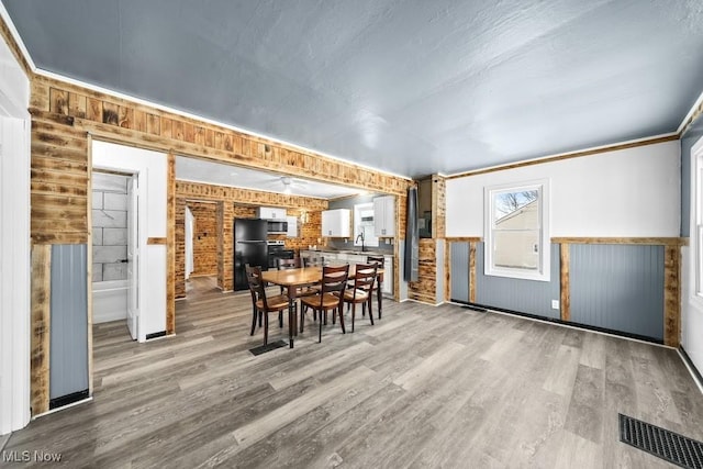 dining area featuring brick wall, hardwood / wood-style flooring, and sink