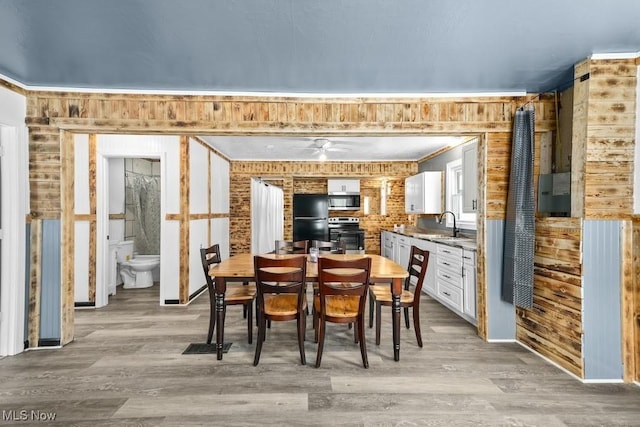 dining room with brick wall, light hardwood / wood-style floors, and sink