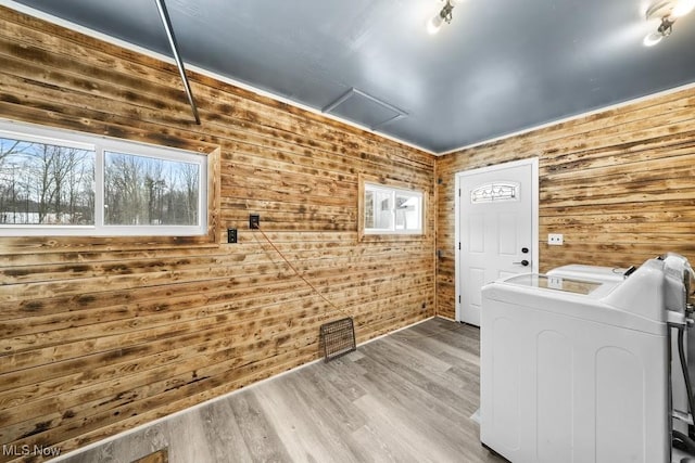 laundry room with hardwood / wood-style floors, washer and clothes dryer, and wooden walls