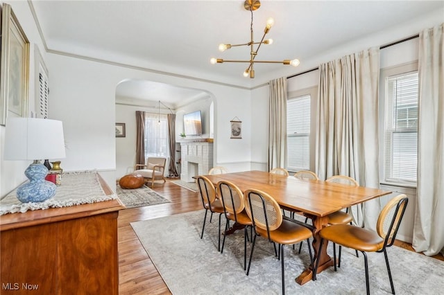 dining room with a fireplace, light wood-type flooring, and a chandelier