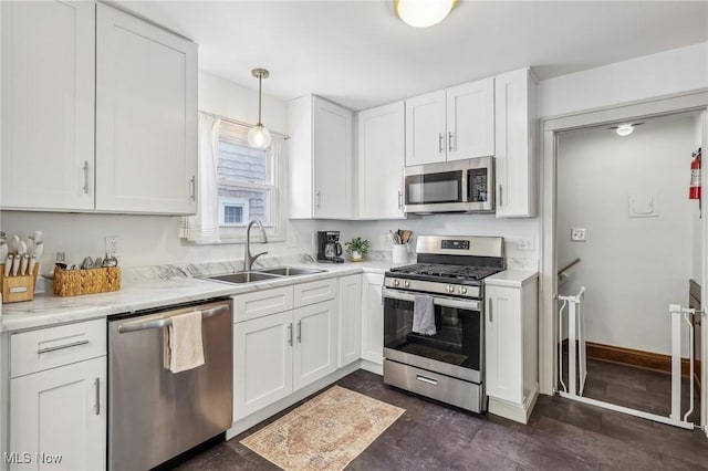 kitchen featuring light stone countertops, decorative light fixtures, stainless steel appliances, white cabinetry, and sink