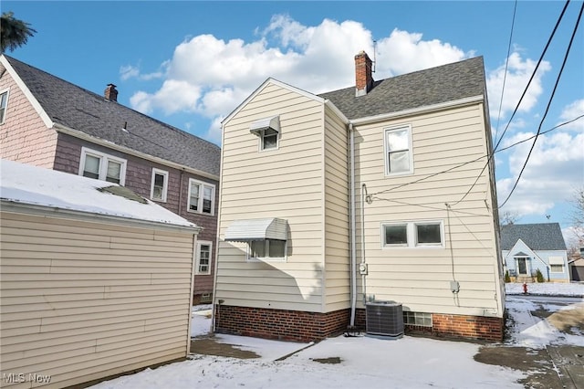 snow covered house featuring central AC unit